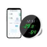Thermomètre connecté wifi avec affichage LED de forme ronde. Les écritures vertes sont sur l'écran noir. Un téléphone sur la gauche.